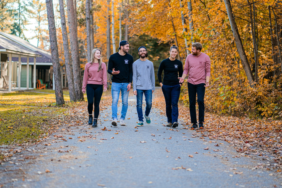 Fem vänner promenerar längs en höstig väg