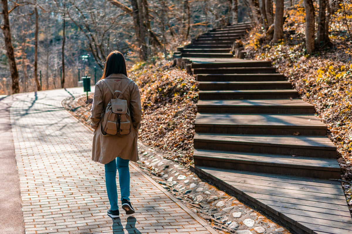Kvinna promenerar bredvid en trappa i en park