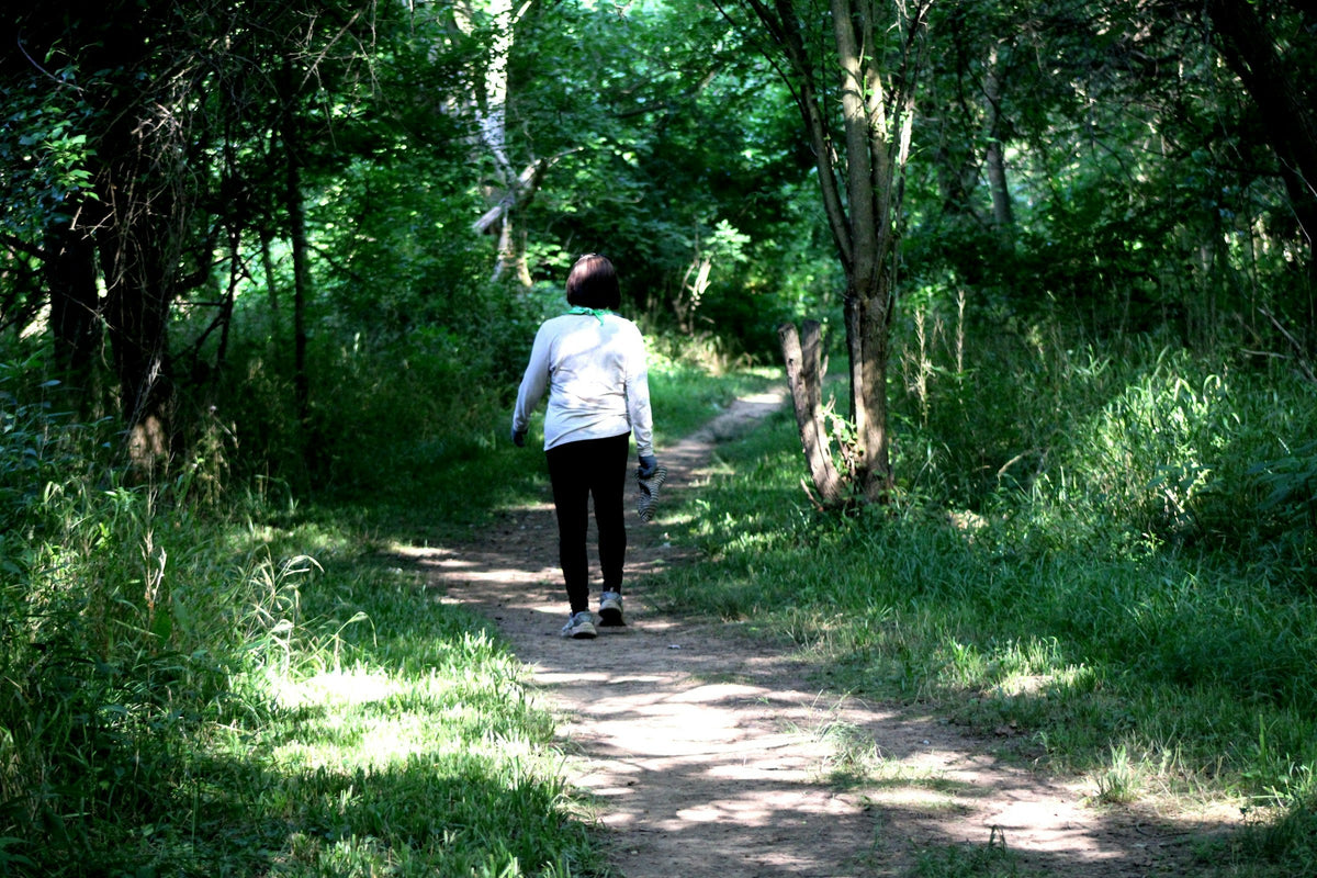 Person promenerar på en grön skogsstig