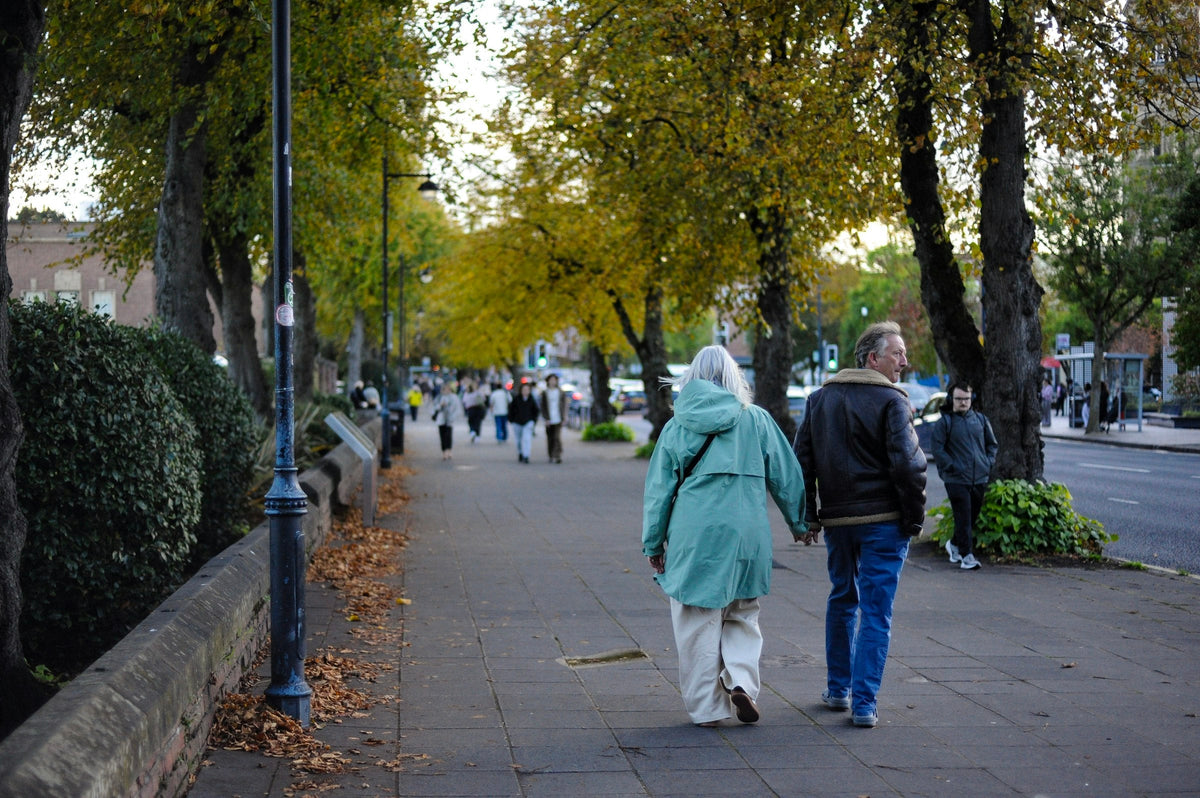 Äldre par promenerar hand i hand på en trottoar