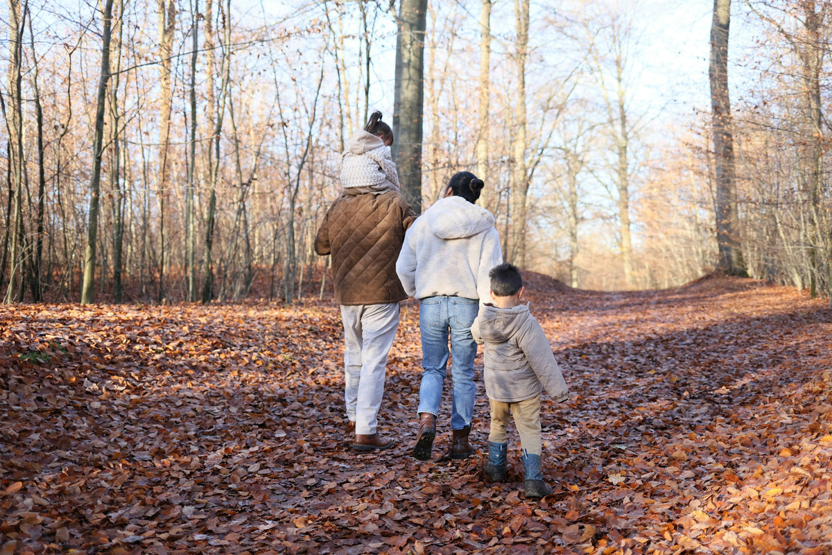 Familj promenerar på en stig täckt av höstlöv